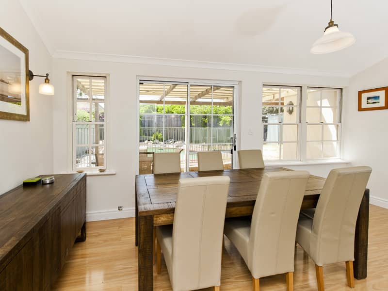 A white dining area finished off with floor boards and cream chairs