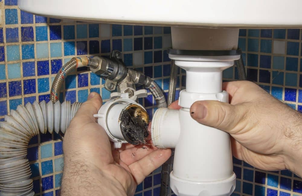 Hand disassembling pipe under the sink.